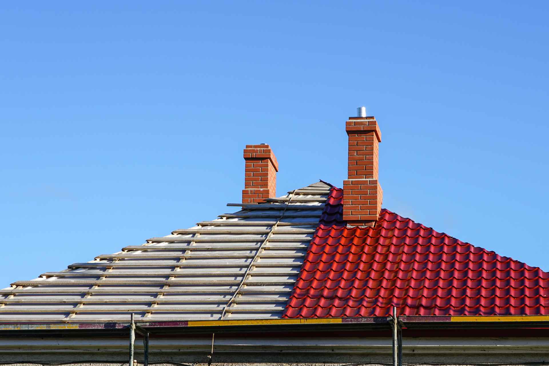 Red roof replacement project showing half-finished new installation and exposed structural framework.